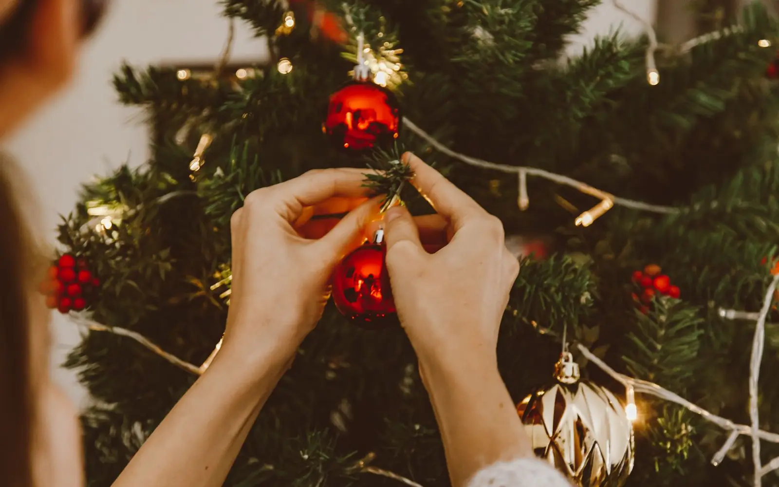 Accrochage d'une boule rouge sur un sapin illuminé