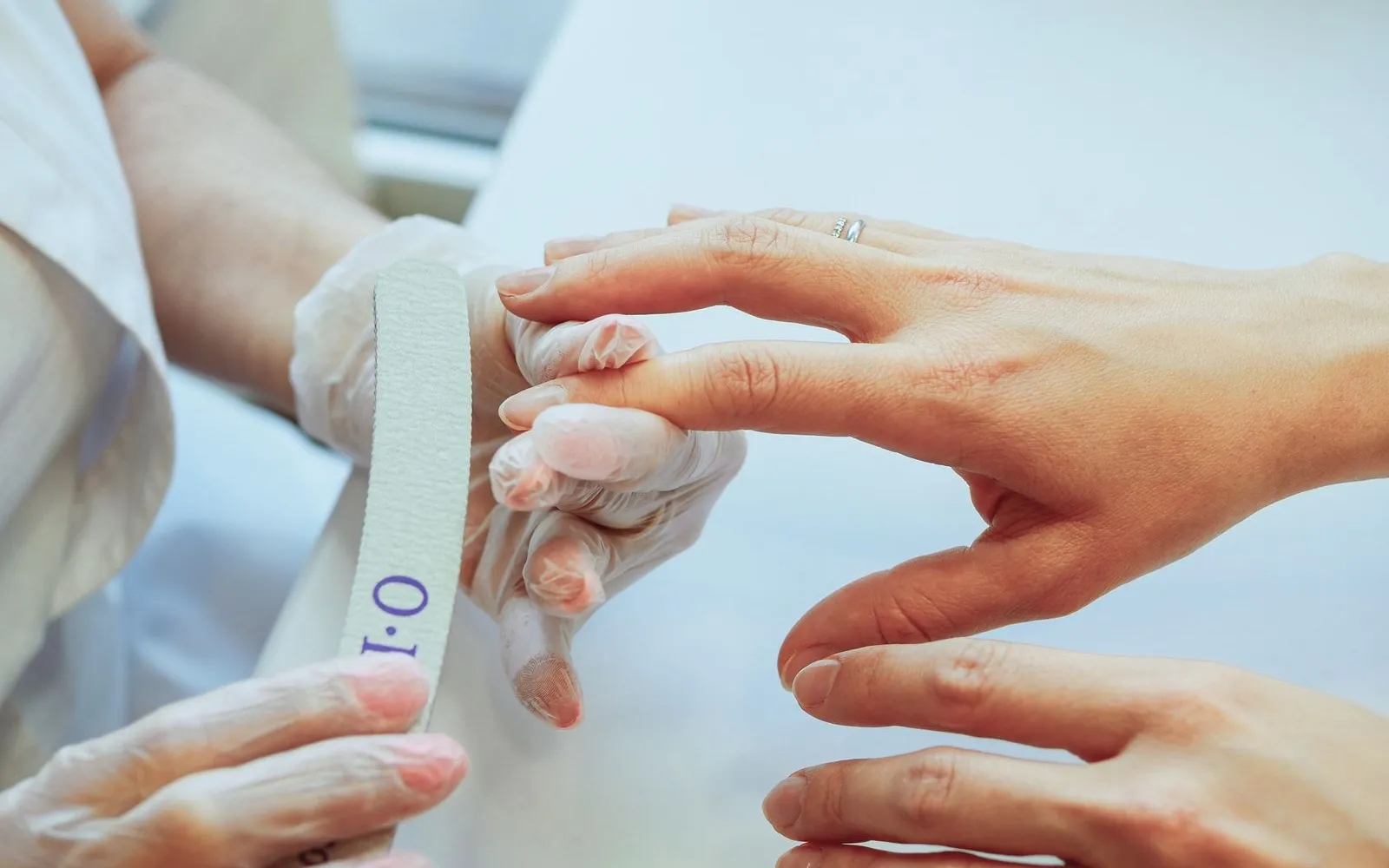 Une prothésiste ongulaire lime les ongles d'une cliente