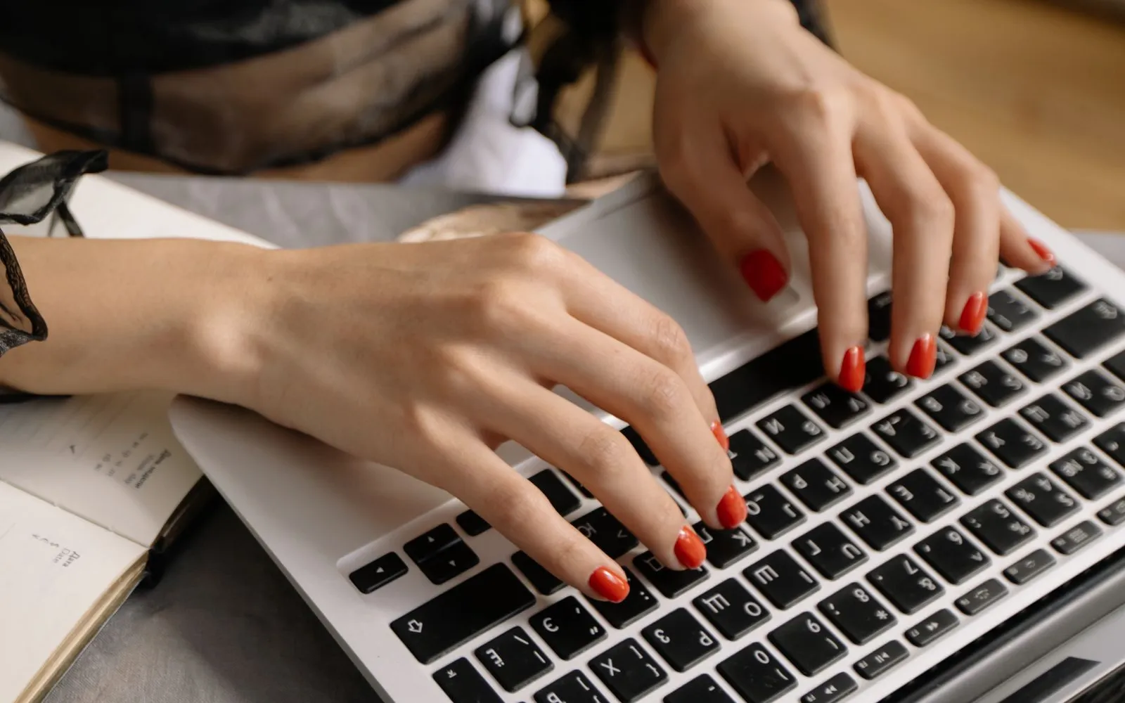 Manicured hands updating a salon website on a laptop