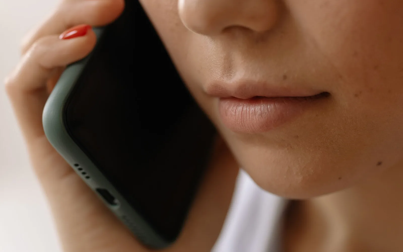 Woman with red nail polish holding a phone to her ear during a call