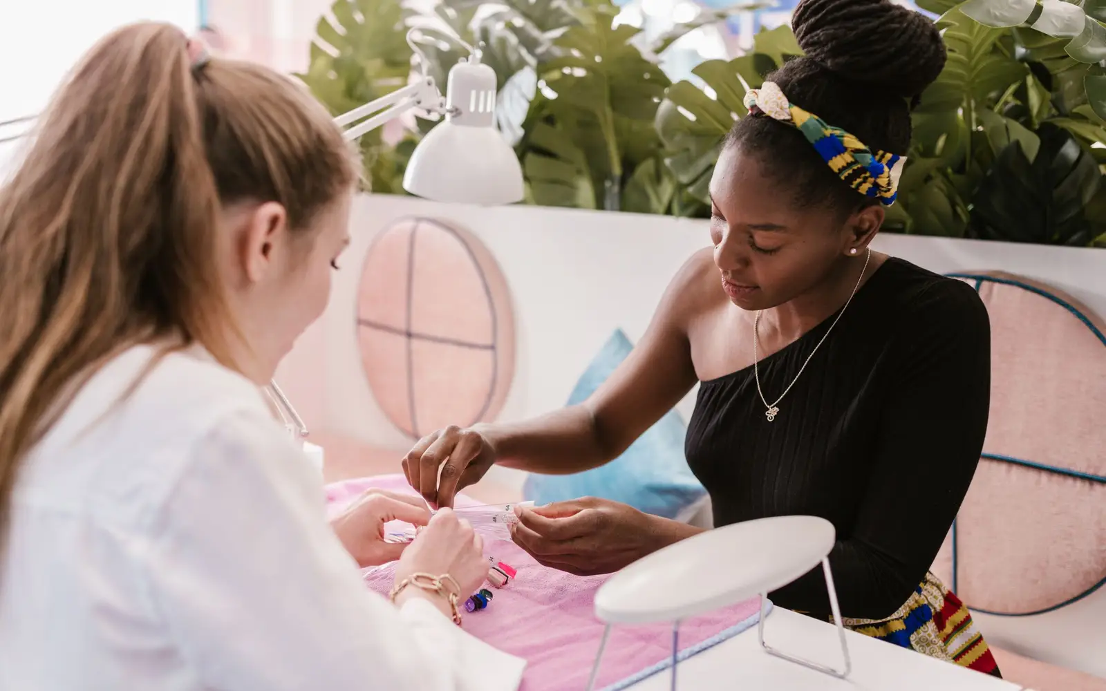 Nail technician working on a client's nails at a salon table