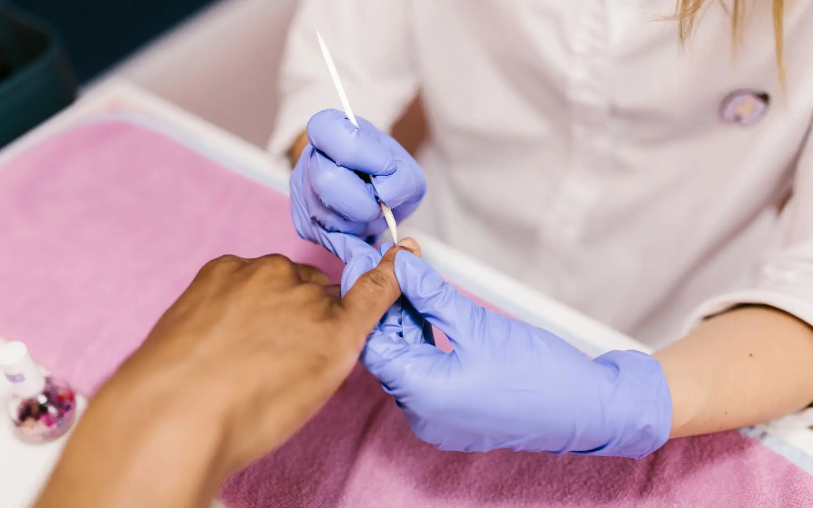Manicure de luvas lixando as unhas de uma cliente